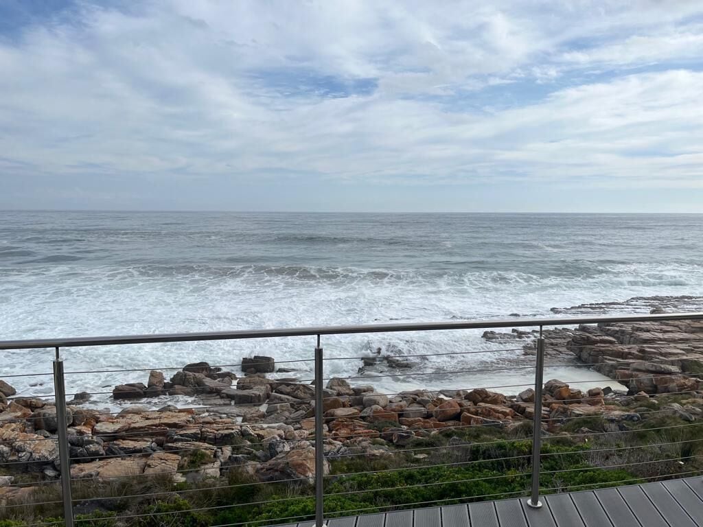 A coastal view with a rocky shoreline and a metal railing.