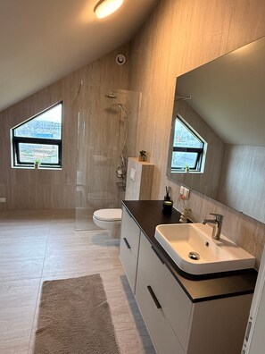A modern bathroom with a shower, toilet, and sink, featuring a large mirror and two windows. - Charming Holiday House in Álftarnes Iceland With Scenic Views (Garðabær)