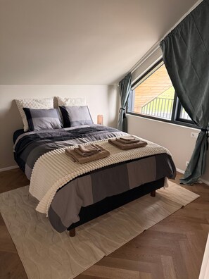 A bedroom with a bed, pillows, a bedside lamp, a window with curtains, and a view of the outside. - Charming Holiday House in Álftarnes Iceland With Scenic Views (Garðabær)