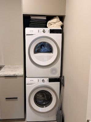 A stacked washer and dryer unit with a marble countertop below. - Charming Holiday House in Álftarnes Iceland With Scenic Views (Garðabær)