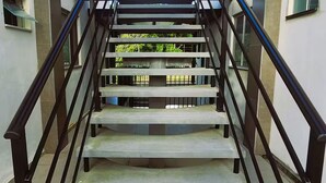 Eine Treppe mit schwarzen Geländern, die zu einem Balkon mit Klimaanlagen führt.