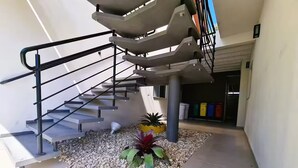 Eine moderne Treppe mit Metallgeländern, ein Kiesweg und ein Blumentopf.