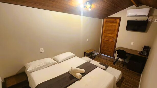 Ein Schlafzimmer mit Bett, Nachttisch, Schreibtisch, Stuhl und einer Klimaanlage.