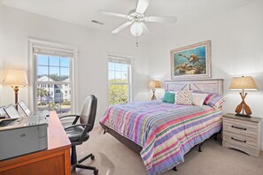 Ein Schlafzimmer mit Bett, Schreibtisch, Stuhl und Deckenventilator.