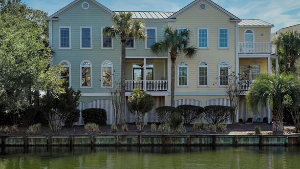 A two-story house with a balcony, a small porch, and a pond in front. - WINTER RENTER AMENITIES INCLUDED 4 bdr Elevator 8500 monthly Seabrook Charleston (Seabrook Island)