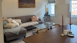 A living room with a sofa, a dining table, and a painting on the wall. - Spacious two bedroom, split level flat in the heart of Wandsworth. (London)