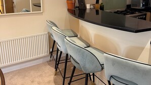 A modern kitchen with a central island, bar stools, a large window, and a built-in stove. - Spacious two bedroom, split level flat in the heart of Wandsworth. (London)