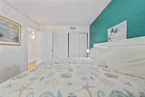 A bedroom with a bed, a door, and a wall with a painting. - The Ocean Escape | Prime Myrtle Beach Getaway (Myrtle Beach)