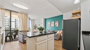Een moderne keuken met een zwarte koelkast, een wand in teal en een eethoek met een tafel en stoelen.