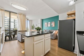 Eine moderne Küche mit einem schwarzen Kühlschrank, einer Wand in Türkis und einem Essbereich mit Tisch und Stühlen.