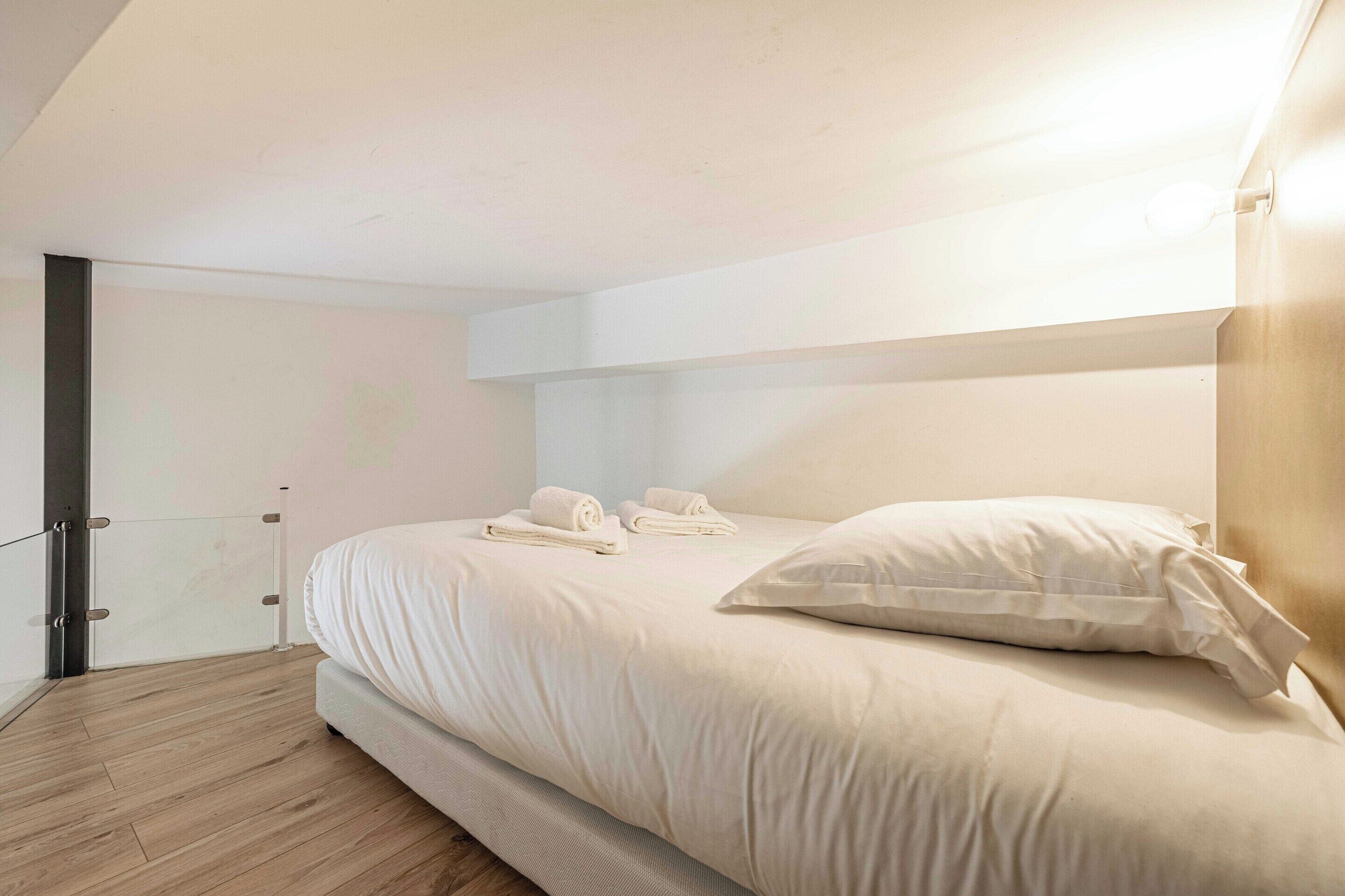 A bedroom with a bed, pillows, and a neatly made bedspread.
