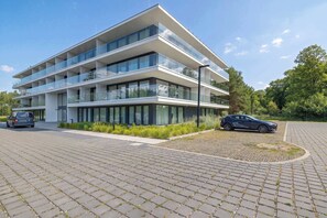 A multi-story building with a modern architectural design, featuring balconies and large windows. - Modern Studio with Air Conditioning | Close to the Beach (Mielno)