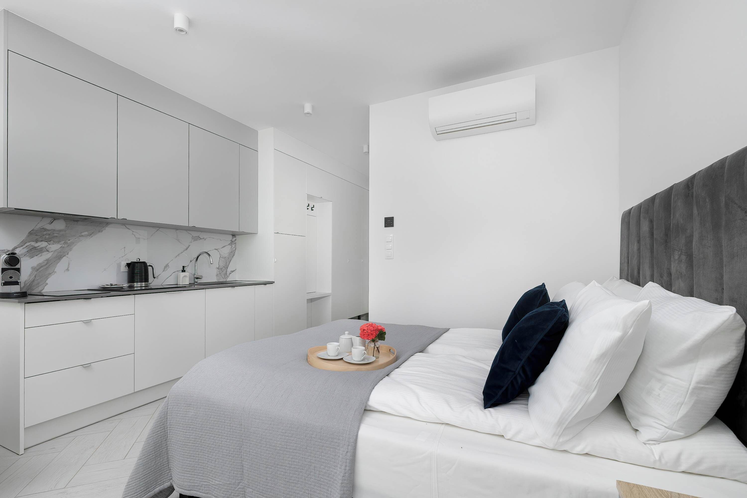 Una camera da letto moderna con un letto, un comodino e vista su una cucina minimalista.