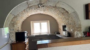 Une cuisine avec une arche en pierre, une fenêtre et un réfrigérateur.