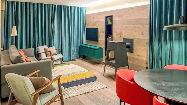 Een moderne woonkamer met een bank, fauteuils, een pooltafel en een televisie.