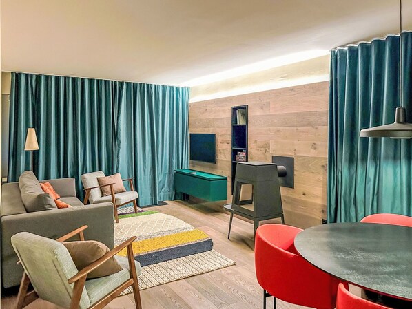 Ein modernes Wohnzimmer mit einer Couch, Sesseln, einem Billardtisch und einem Fernseher.