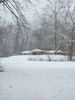 A snow-covered landscape with a house and trees.