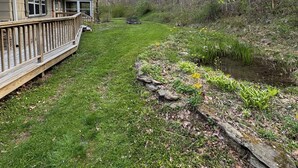 A house with a deck, a small pond, and a forested area. - Private 12-Acre Mountain Retreat - Hot Tub, Pond & Creek minutes from Asheville (Weaverville)