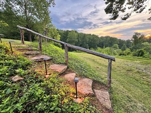 A wooden staircase with metal railings leading up a grassy slope.