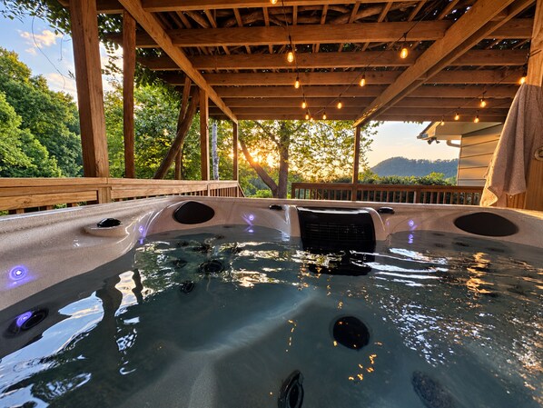 A hot tub with a wooden deck and a view of the outdoors.