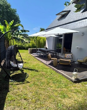 A deck with outdoor furniture, a swing chair, and a covered seating area. - A beautiful, spacious house near the ocean (Ploemeur)