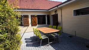 En terrasse med et bord og stole, et rødt tegltag og en skorsten.