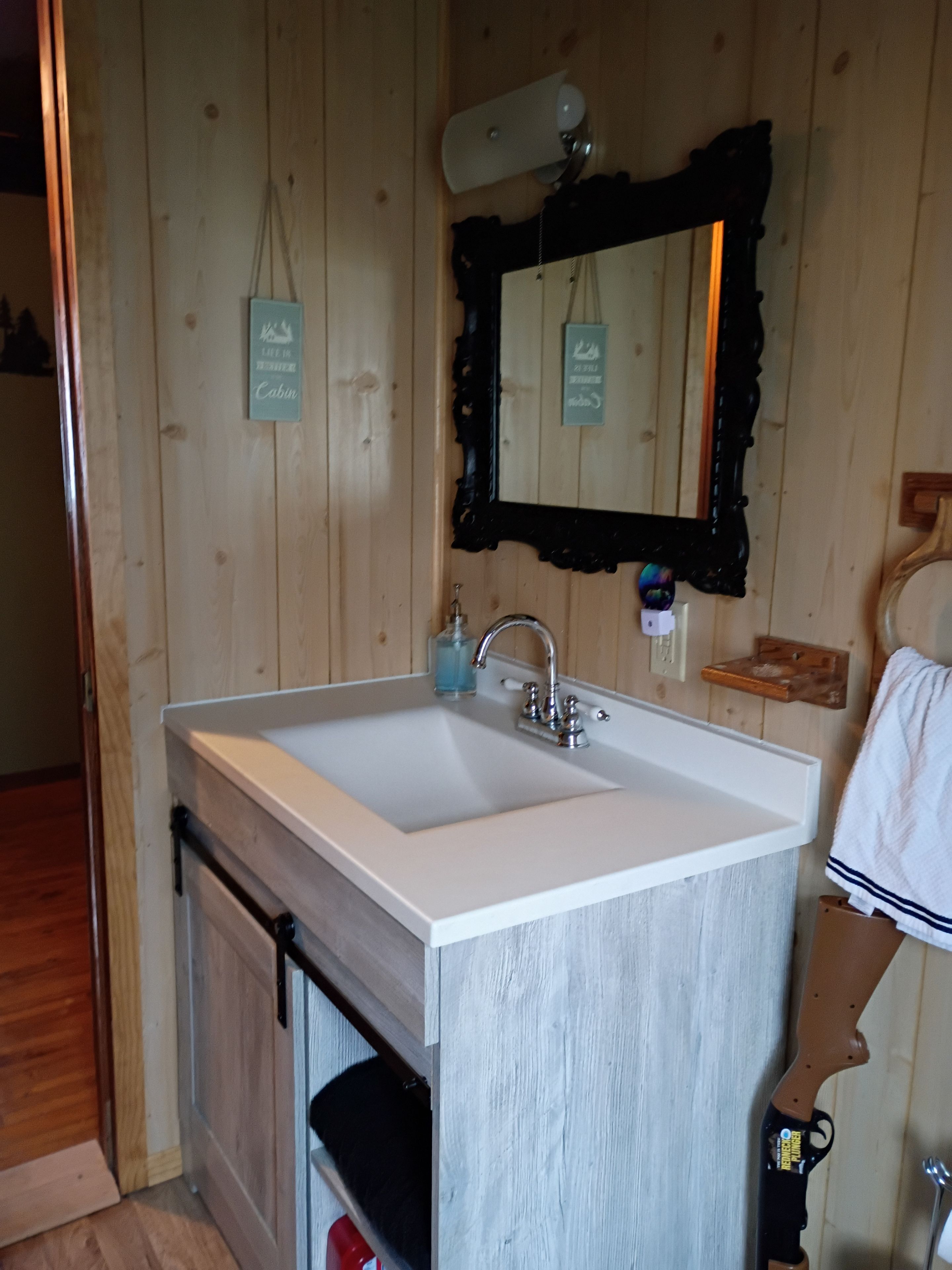 A bathroom with a white sink, a mirror, and wooden walls.