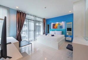 A modern hotel room with a large bed, a desk, and a television.
