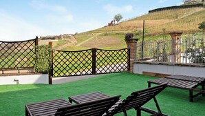 Een terras op het dak met kunstgras, houten banken en uitzicht op een glooiend landschap.