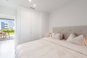 A bedroom with a large bed, a nightstand, and a view of the outdoors. - Alicia | Garden & Pool View, Fuengirola (Fuengirola)
