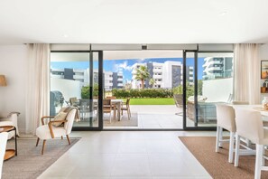 A modern living room with a glass door leading to an outdoor patio area. - Alicia | Garden & Pool View, Fuengirola (Fuengirola)