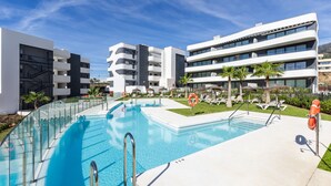 A modern hotel with a swimming pool, sun loungers, and palm trees. - Higuerón West Alicia | Modern Apartment with Garden & Pool View (Fuengirola)