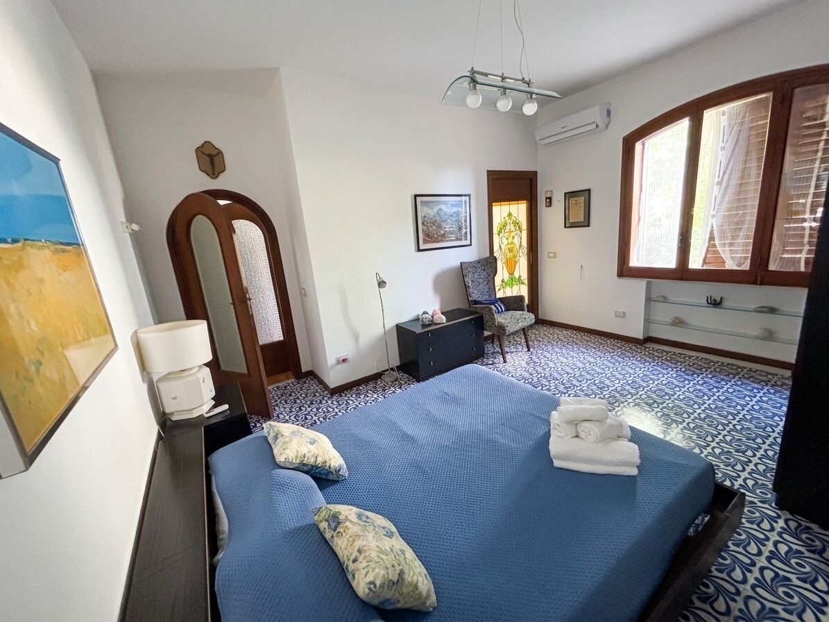 Ein Hotelzimmer mit Bett, Schreibtisch, Stuhl, einem Fenster mit Vorhängen und einer Tür.