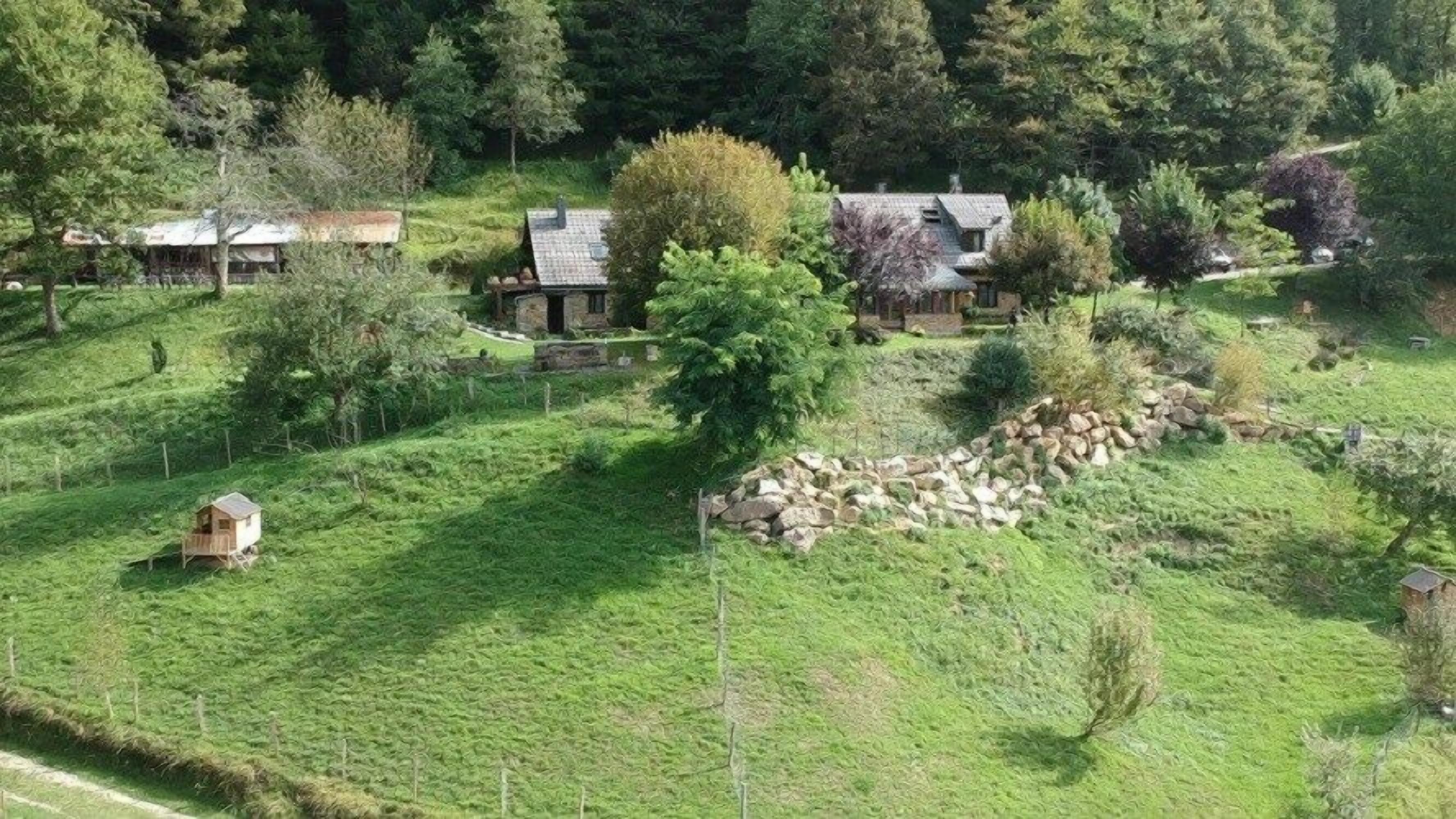 A rural landscape with houses, a stone wall, and a fenced area.