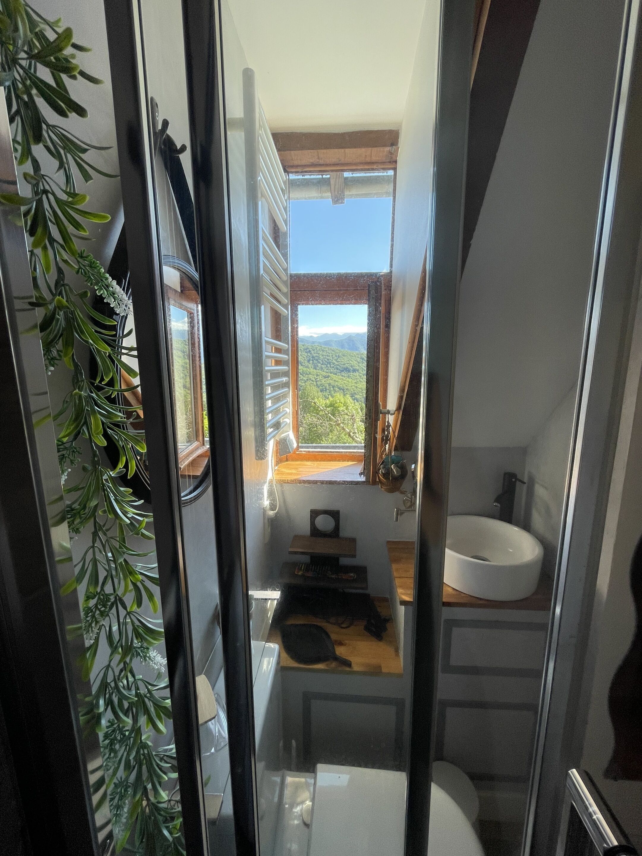 Une petite salle de bain étroite avec une fenêtre, un lavabo et une petite étagère en bois.