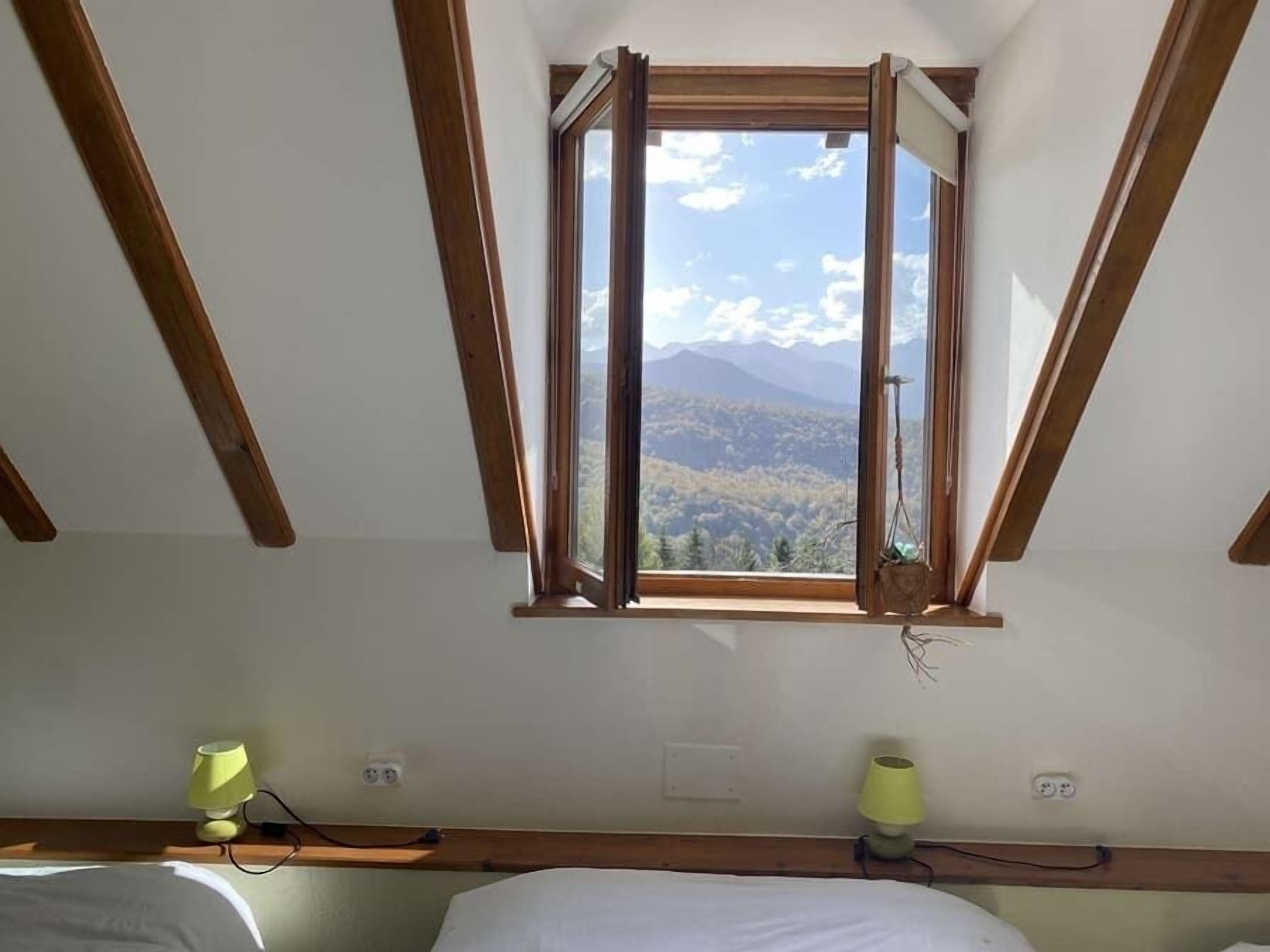 A bedroom with a skylight, a bed, and a bedside table with a lamp.