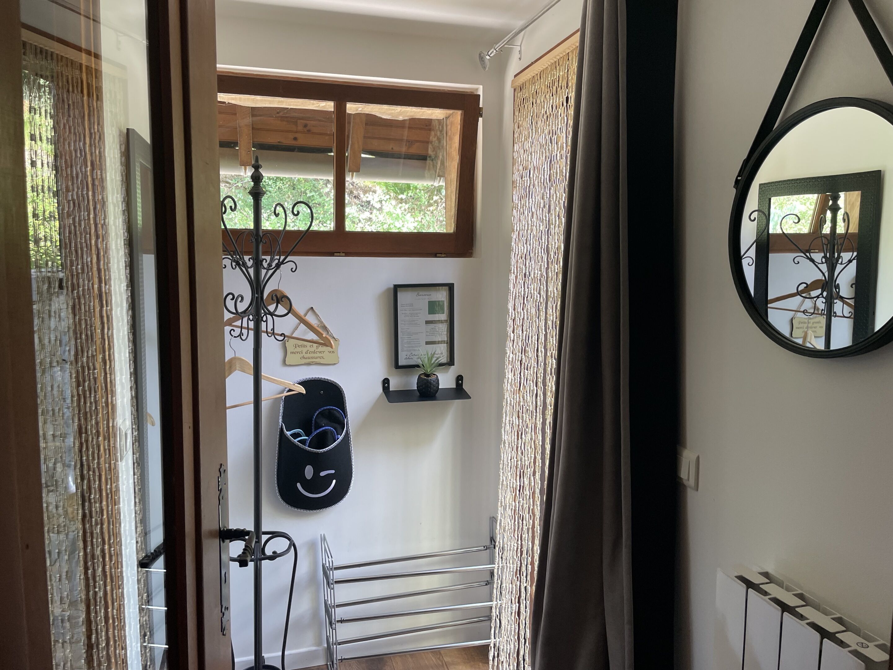 A hallway with a coat rack, a framed menu, a mirror, and a radiator.
