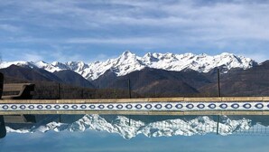 A pool with a mountain view, a tiled edge, and a clear sky. - La Bernadole (Aleu)