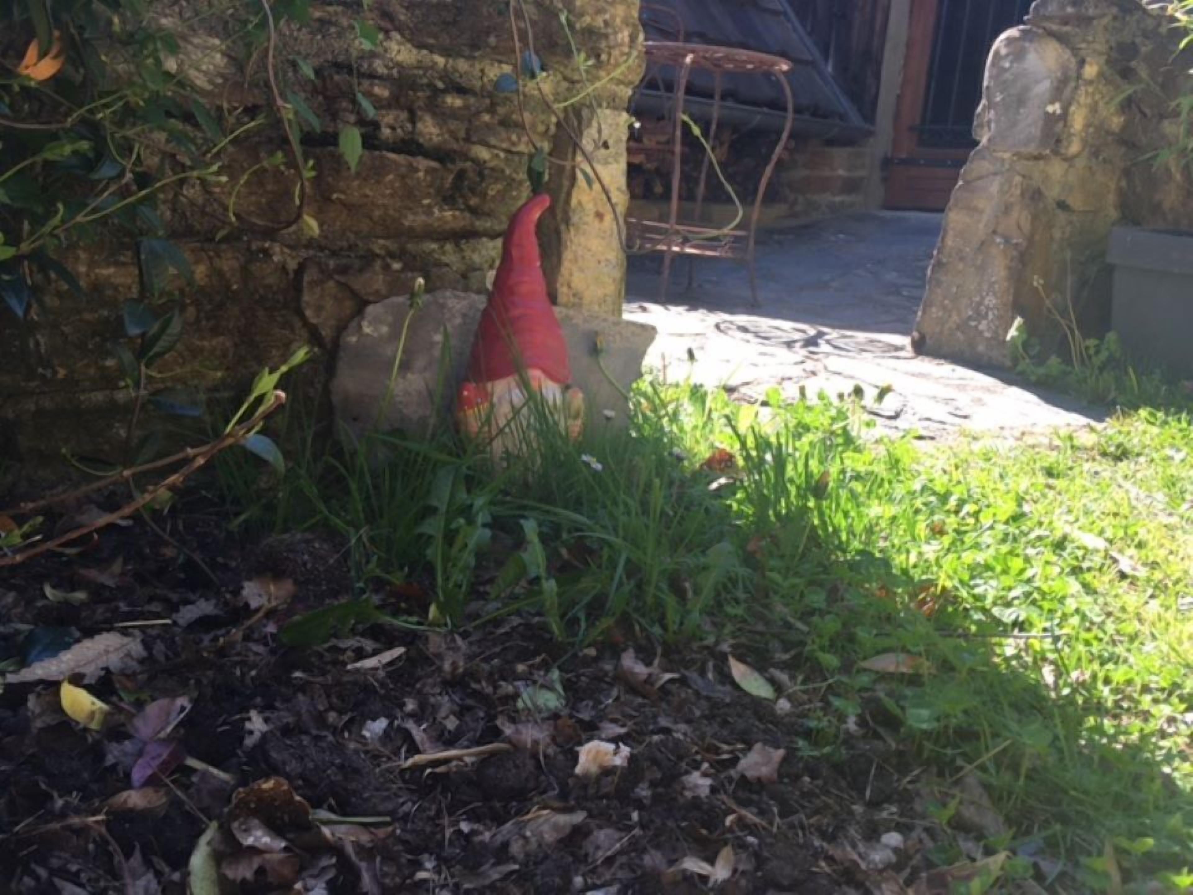 A garden area with a stone wall, a red decorative object, and a metal table.