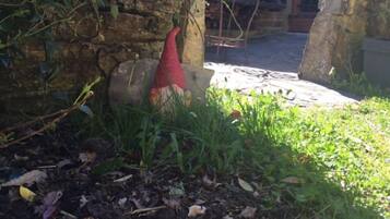 A garden area with a stone wall, a red decorative object, and a metal table.