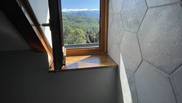 Un baño con tragaluz, banco de madera, planta en maceta y lavamanos blanco.
