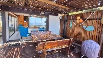 Un área de estar al aire libre cubierta, con bancos de madera, una mesa y sillas.
