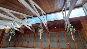 A room with wooden beams, frosted glass cabinets, and hanging plants. - Anca on C With Seaview (Klein Brak River)