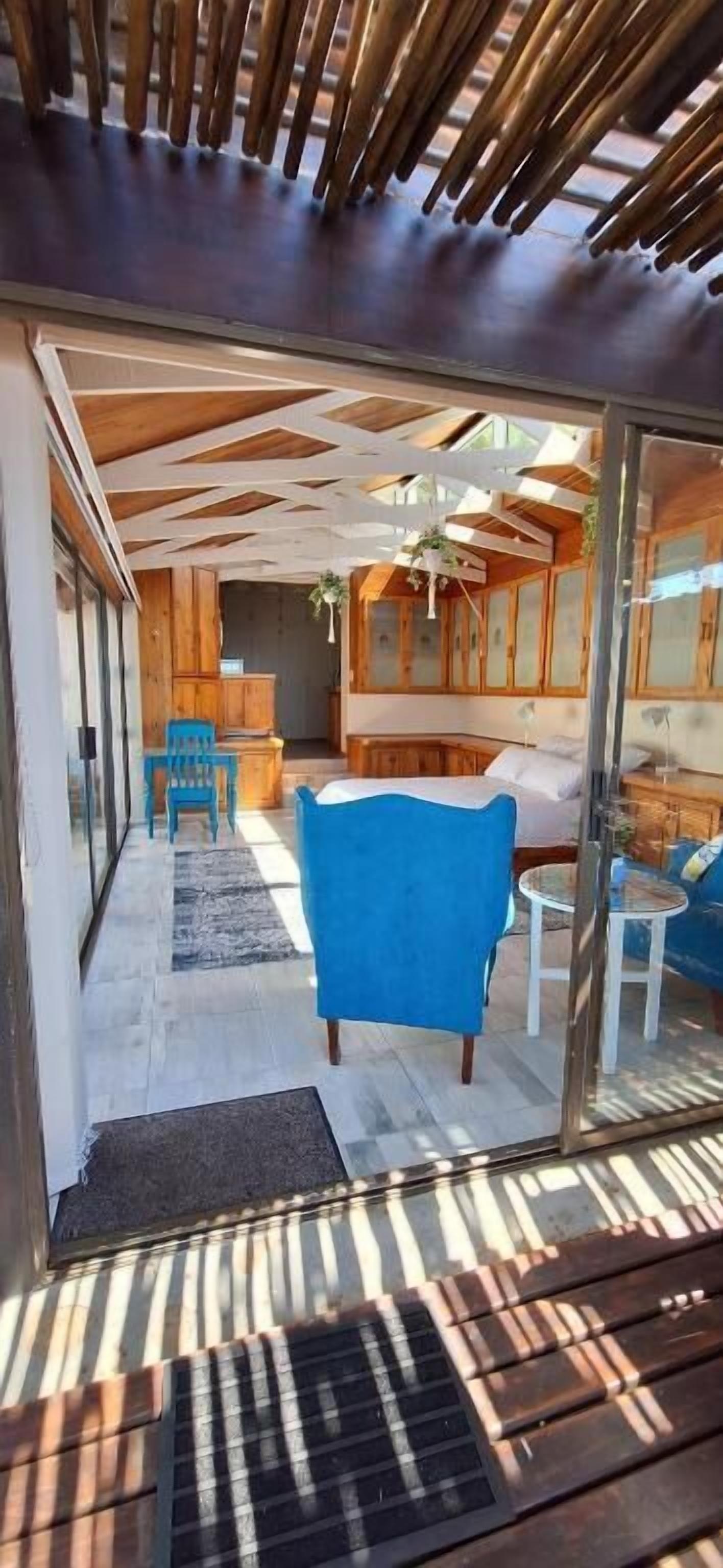 A modern interior with a wooden ceiling, glass doors, a blue chair, and a small round table.