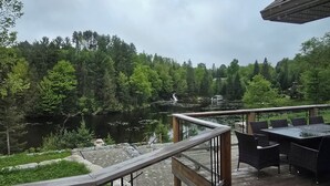 A wooden deck with outdoor furniture overlooking a lake and forest.