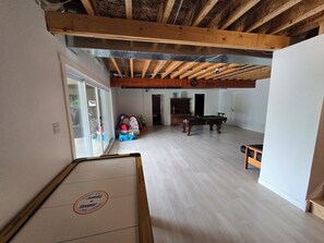 A spacious room with a wooden ceiling, a pool table, and a billiards table.