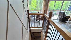 A wooden staircase with a railing, leading to a deck area with outdoor furniture.