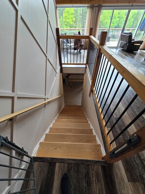 A wooden staircase with a railing, leading to a deck area with outdoor furniture.