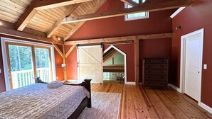 Un dormitorio con techo de madera, una cama, un aparador y vistas a un balcón.