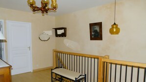 Ein Zimmer mit einer hölzernen Sitzbank, einer weißen Tür, einer Chandelierleuchtreibe und einem gerahmten Bild an der Wand.